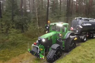 Obrněný zelený traktor John Deere s cisternou na lesní cestě