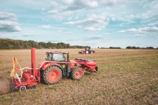 Červený traktor se secím strojem Kverneland při práci na poli
