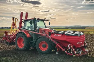 Červený traktor se secím strojem Kverneland na poli