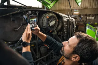 Muž fotografuje mobilním telefonem náhradní díl traktoru Fendt