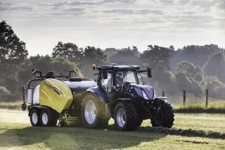 Traktor New Holland s lisem Roll Baler a ovíječkou na louce