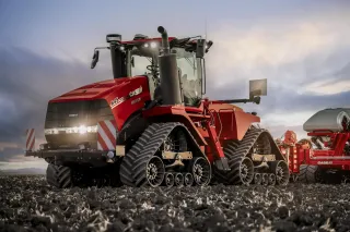 Červený pásový traktor Case IH Quadtrac na poli za soumraku