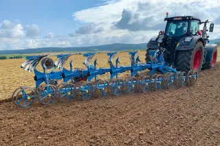 Traktor s modrým pluhem Lemken FlexPack na poli
