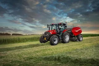 Traktor Case IH s lisem na travnatém poli za soumraku