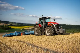 Traktor Massey Ferguson 9S s modrým kypřičem na poli