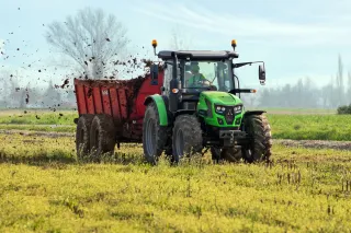 Traktor Deutz-Fahr rozmetá hnůj na poli