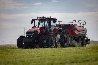 Traktor Case IH táhne lis na balíky na louce.