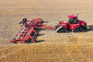 Pásový traktor Case IH s diskovým podmítačem na poli.