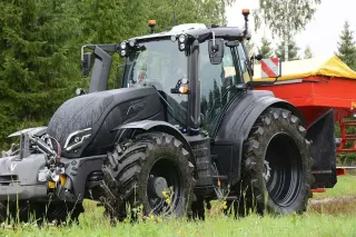 Černý traktor Valtra s červeným rozmetadlem.