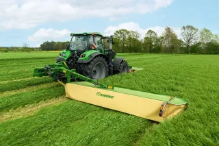 Traktor se žacím strojem Krone EasyCut seče louku.