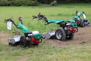 Tři zelené jednoosé traktory Ferrari na trávníku.