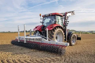 Traktor s rotační plečkou Fliegl na poli.