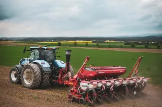Traktor s přesným secím strojem Kverneland na poli.