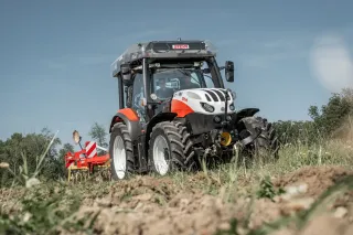 Červený traktor Steyr na poli.