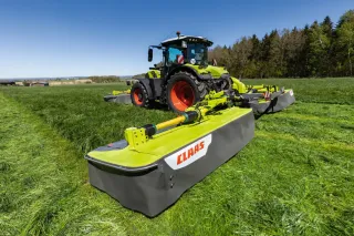 Traktor Claas se žacím strojem Disco na louce.