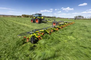 Traktor Claas s širokým obracečem Volto na louce.