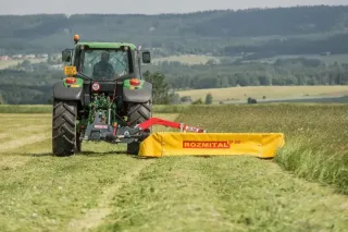 Traktor se žlutým žacím strojem Rozmital na louce.