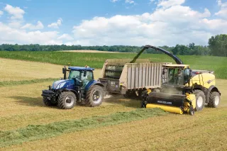 Sklízecí řezačka New Holland sklízí píci vedle traktoru s návěsem.