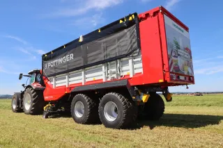 Červený senážní vůz Pöttinger Jumbo 5000 za traktorem.