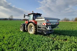 Traktor se zásobníkovým rozmetadlem SKY Agriculture na poli.