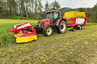 Traktor se žacím strojem Pöttinger při sečení louky.