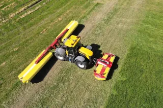 Traktor se žacími stroji Pöttinger při sečení louky.