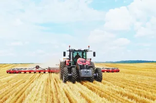 Traktor Massey Ferguson 9S s nářadím při práci na poli.