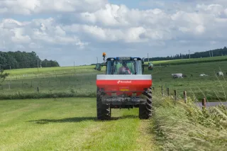 Traktor s rozmetadlem Kverneland na poli.