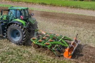 Traktor s kypřičem AMAZONE Cenius na poli.