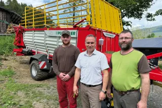 Tři muži před samosběracím vozem Pöttinger