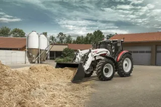 Traktor STEYR s čelním nakladačem u farmy