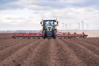 Traktor s prutovými branami Pöttinger na poli