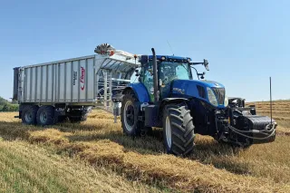 Modrý traktor s návěsem Fliegl Gigant na poli