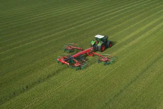 Traktor s čtyřrotorovým shrnovačem Kverneland na louce