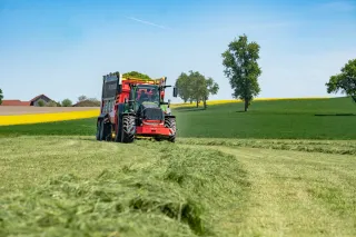 Sběrací vůz Pöttinger se zelenou hmotou na louce