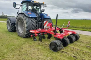Traktor s červeným strojem SMS Agro na louce