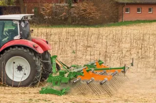 Červený traktor s kultivačním strojem na poli