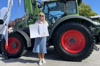 Žena s diplomem před traktorem Fendt na výstavě