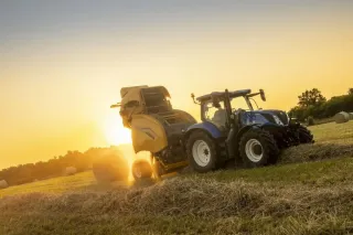 Lis New Holland při práci na poli za západu slunce