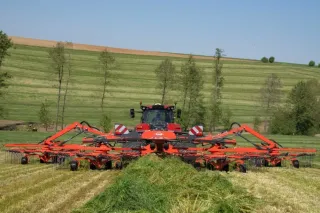 Traktor KUHN se shrnovačem na louce