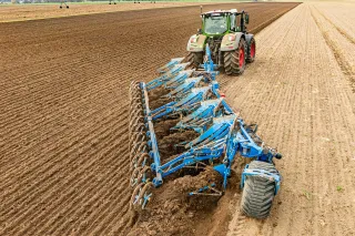 Traktor s modrým pluhem LEMKEN při orbě