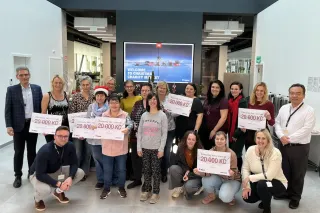 Účastníci charitativního jarmarku Bobcat drží darovací šeky
