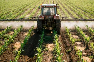 Traktor s postřikovačem při práci na poli