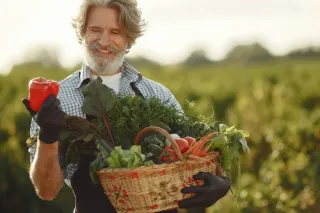 Farmář drží červenou papriku a košík zeleniny