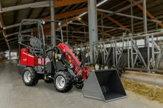 Kompaktní červený nakladač Schäffer ve stáji