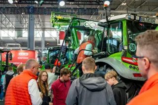 Návštěvníci veletrhu si prohlížejí zelený traktor Fendt s čelním nakladačem.