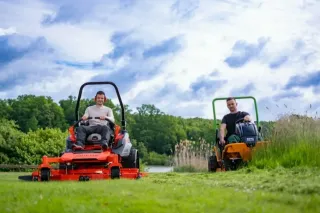 Obsluha na červeném žacím traktoru při práci na trávníku
