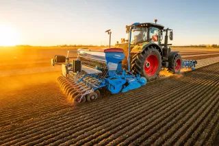 Traktor s modrým secím strojem LEMKEN na poli