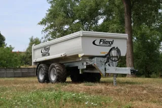 Bílý sklápěcí návěs Fliegl stojící na trávě
