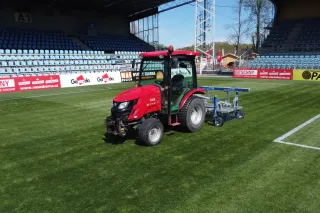 Červený traktor TYM na fotbalovém trávníku